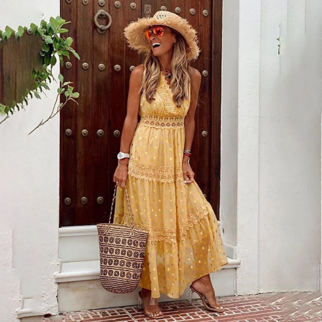 Woman wearing a sleeveless beige lace bohemian maxi dress, standing outdoors, with a summer hat, showcasing the lightweight and flowy design.