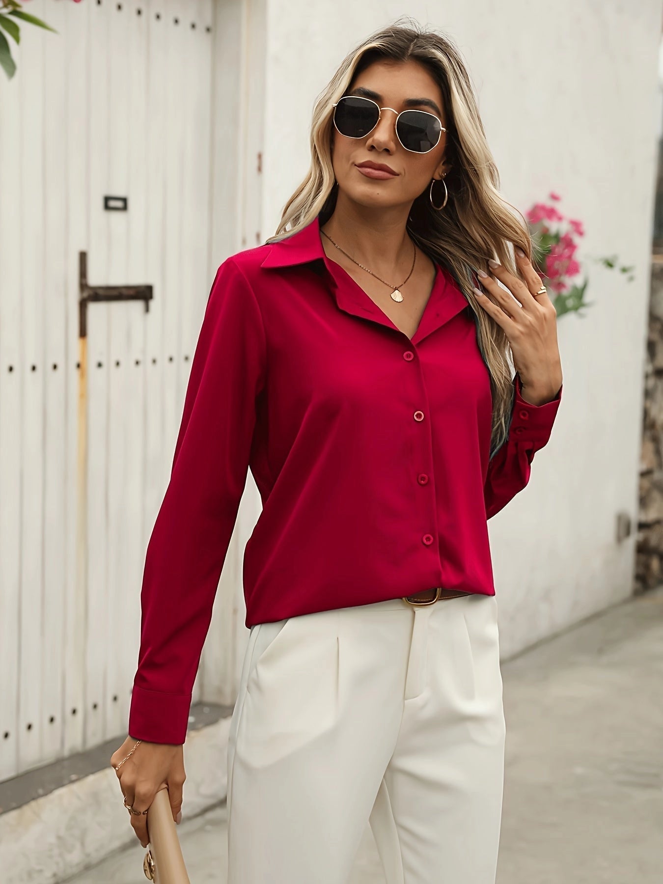 A woman wearing a crimson silk satin blouse with long sleeves in size XXL, paired with sunglasses.