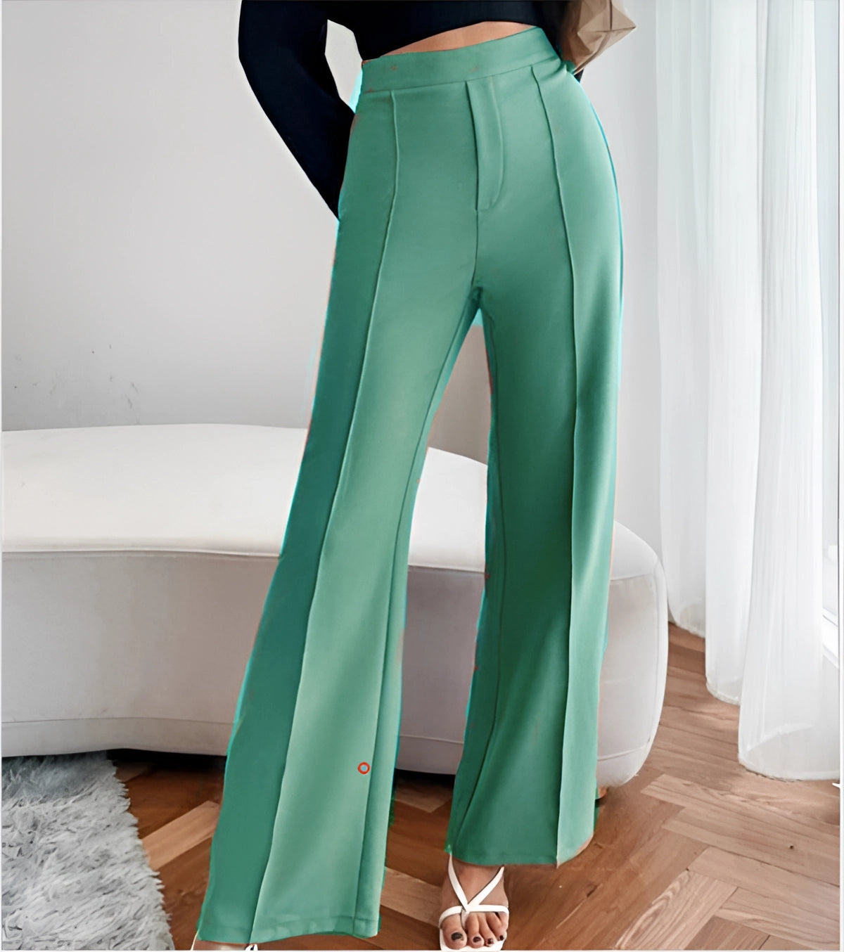 Woman wearing high-waist flared beige trousers, tailored fit for office wear, paired with a green top, showcasing the outfit's fit around the waist, legs, and thighs.