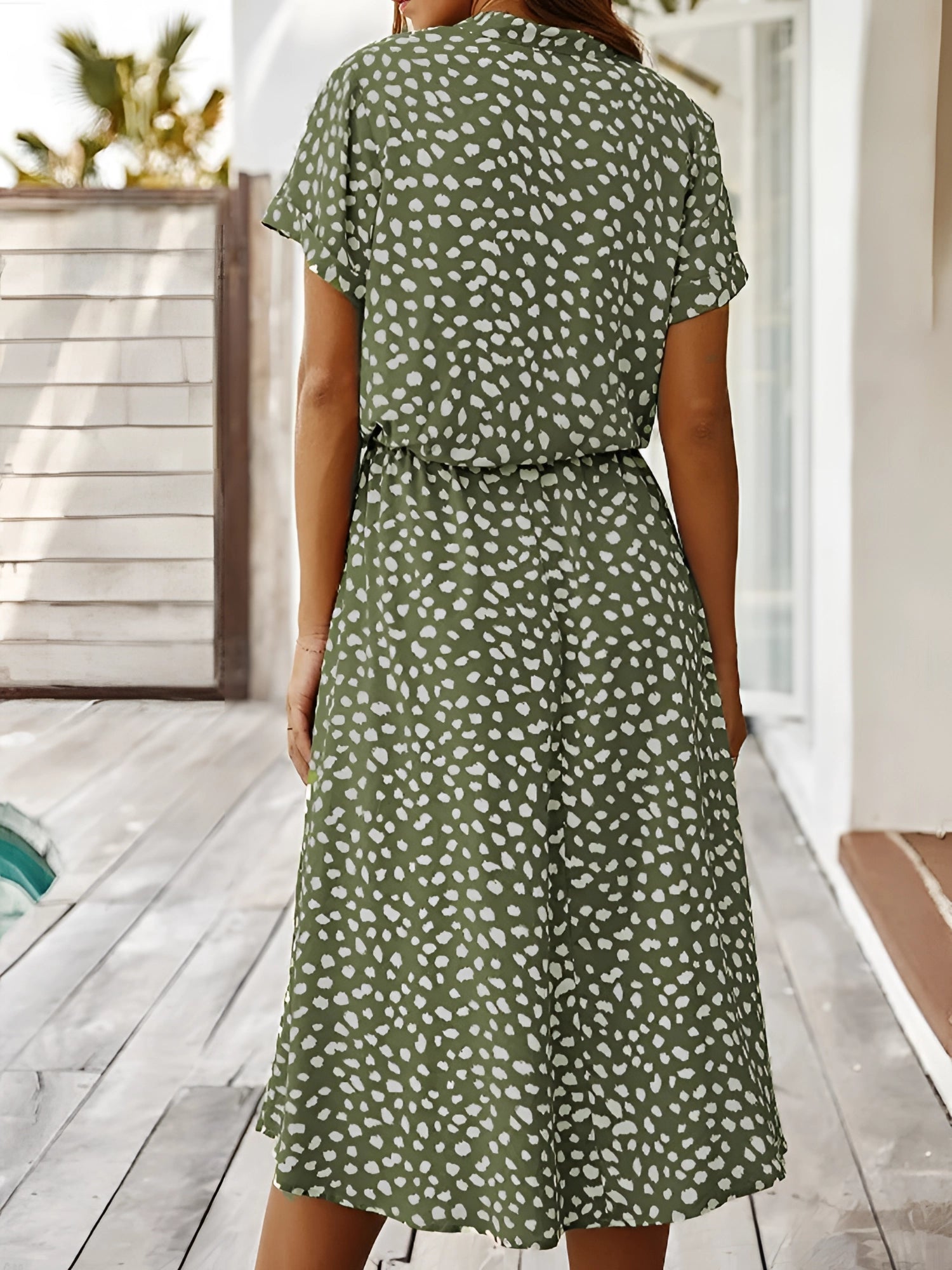 White polka dot midi dress with short sleeves and a tie waist, displayed on a mannequin, perfect for lightweight summer wear.