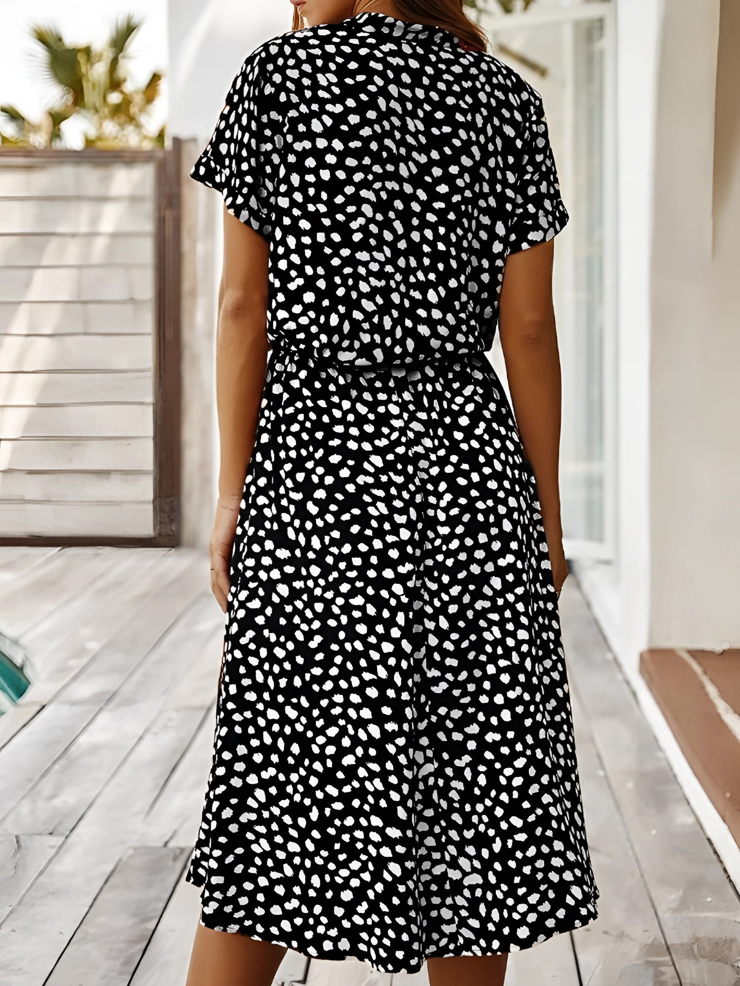 White polka dot midi dress with short sleeves and a tie waist, lightweight summer attire.