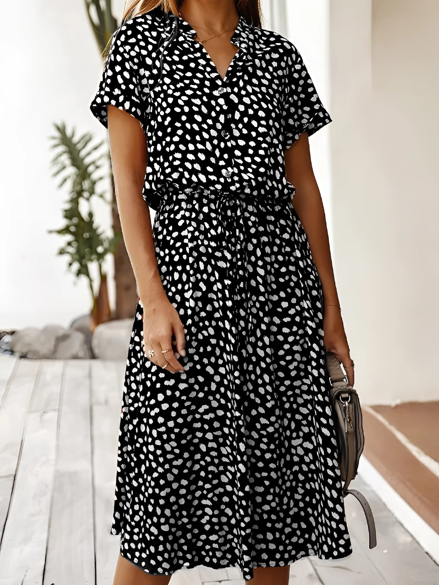 A white polka dot midi dress with short sleeves and a tie waist, perfect for lightweight summer wear.