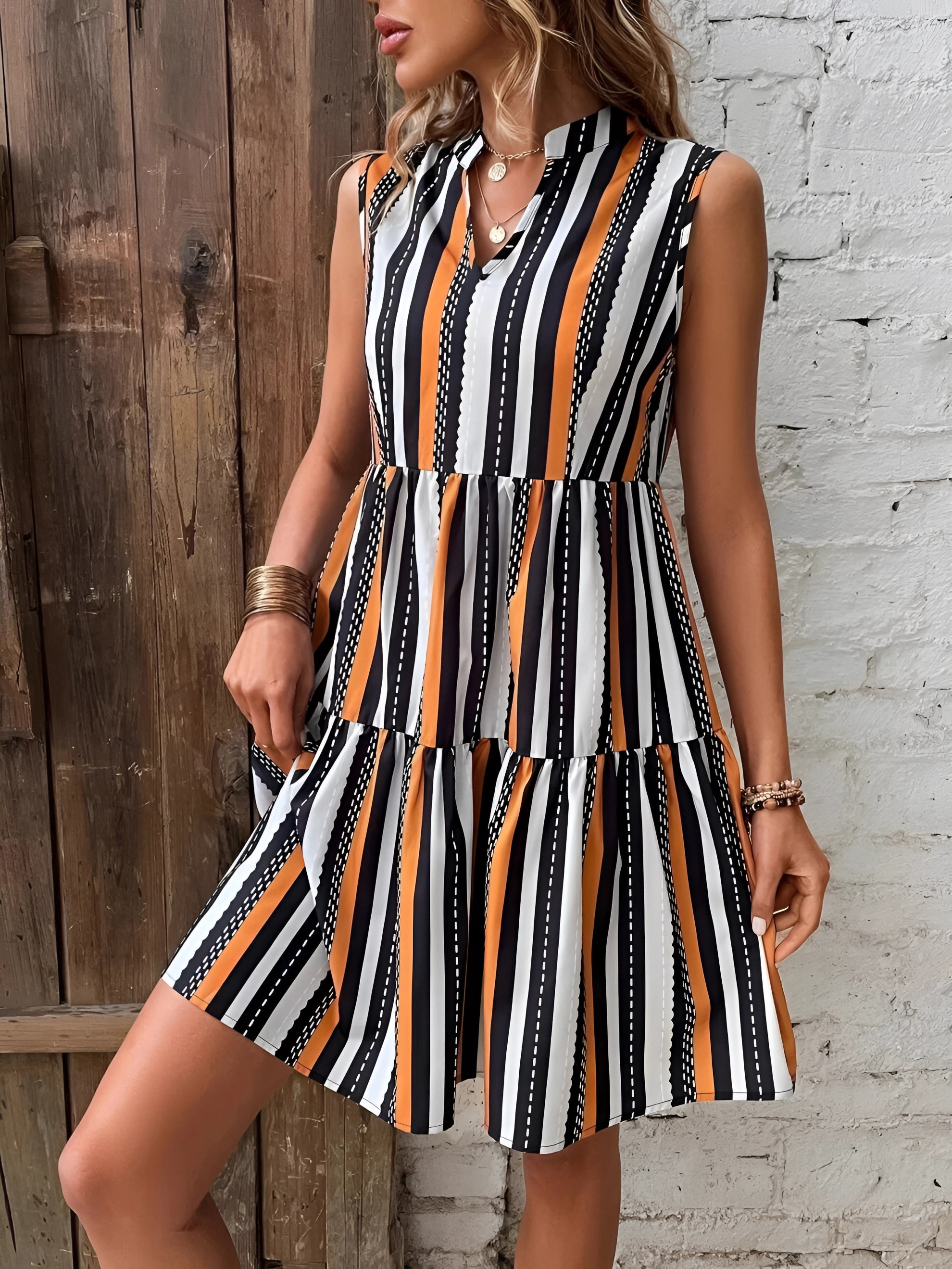 Black, white, and orange striped sleeveless A-line summer dress worn by a person, visible from the neck to the knees.