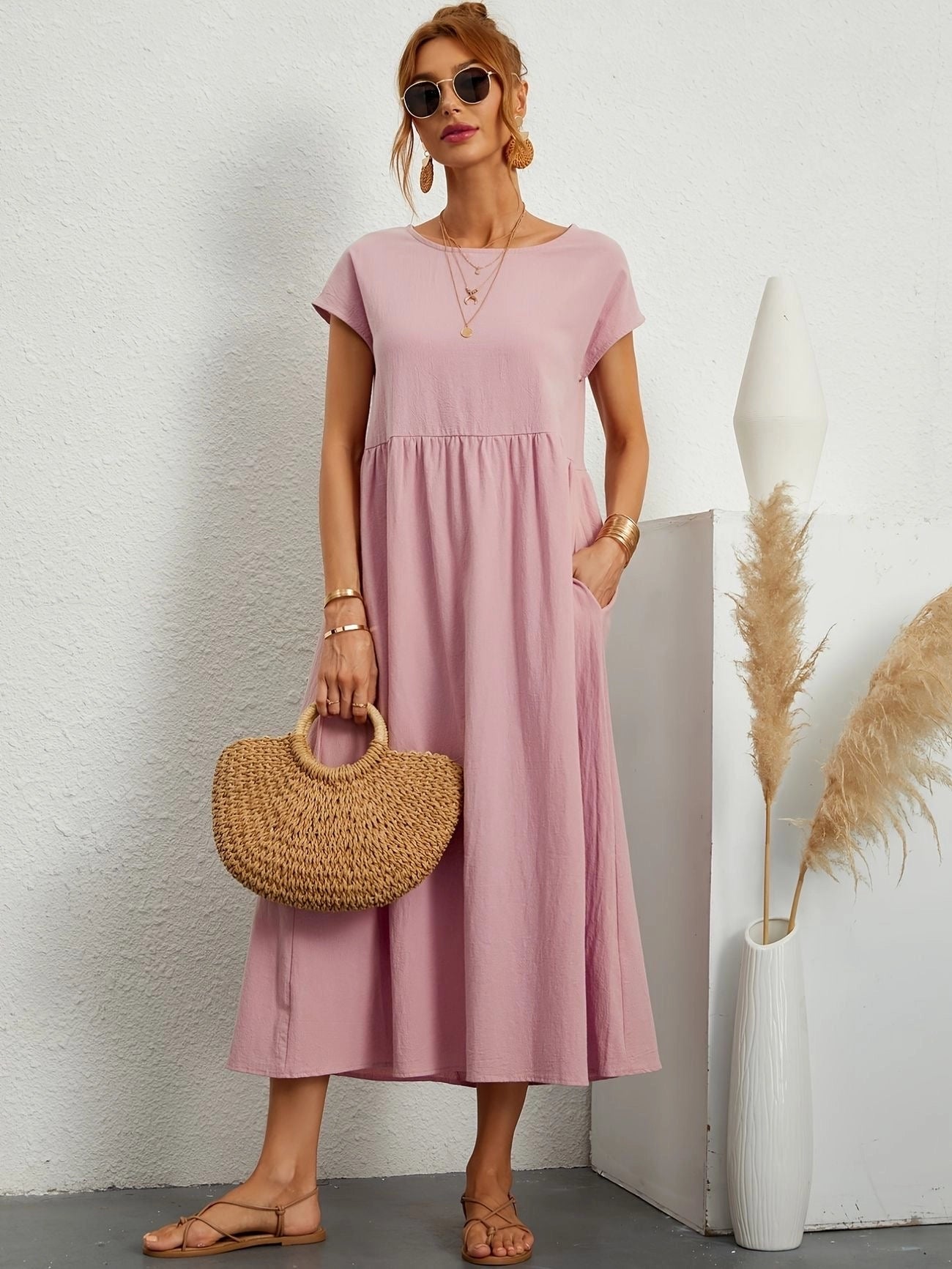 Woman wearing a light pink, short sleeve, crew neck, midi sundress, suitable for casual summer outings.